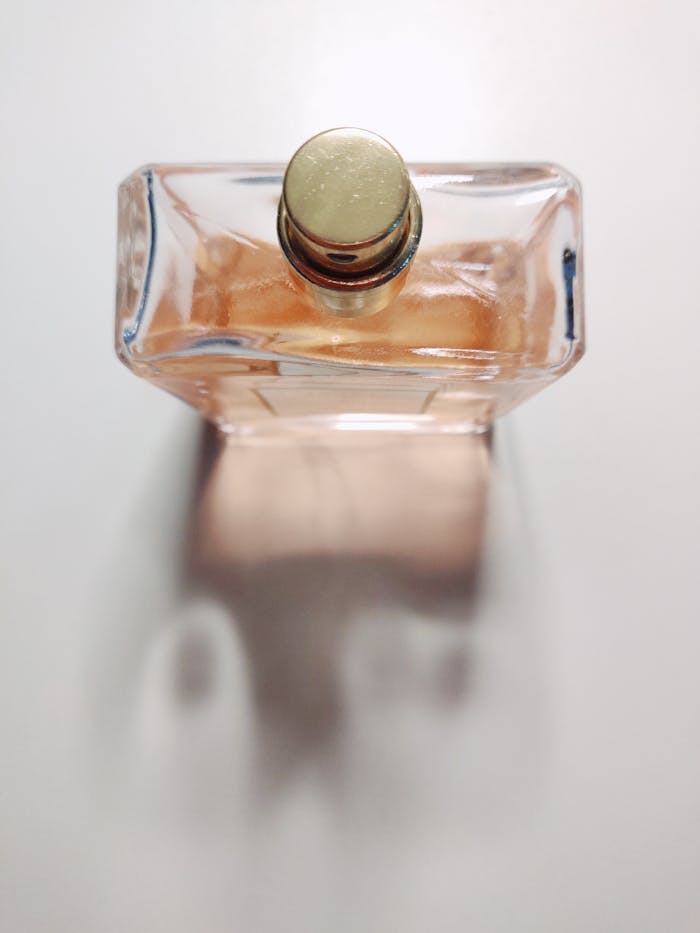 The Art of Drawing Readers In: Your attractive post title goes here A close-up shot of an elegant perfume bottle with a golden cap on a white surface casting a shadow.